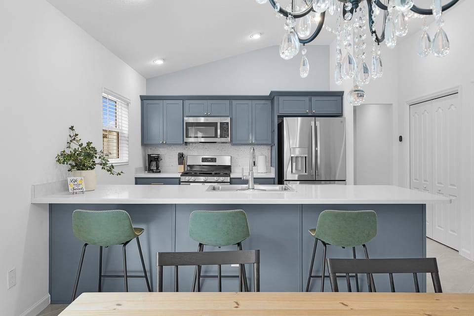 Gather around the elegant island bar for morning coffee or casual meals. Modern appliances, stylish cabinetry, and a sparkling chandelier create your perfect space to cook and connect.