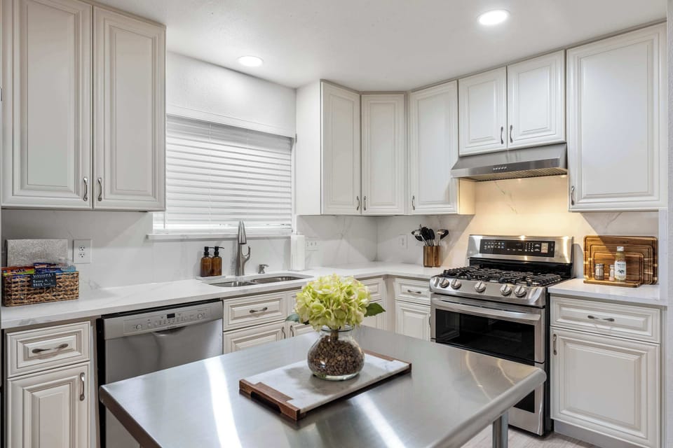 The bright, modern kitchen features quartz countertops, stainless steel appliances, a chef's stainless steel island, and a welcoming eat-in dining space for shared meals.