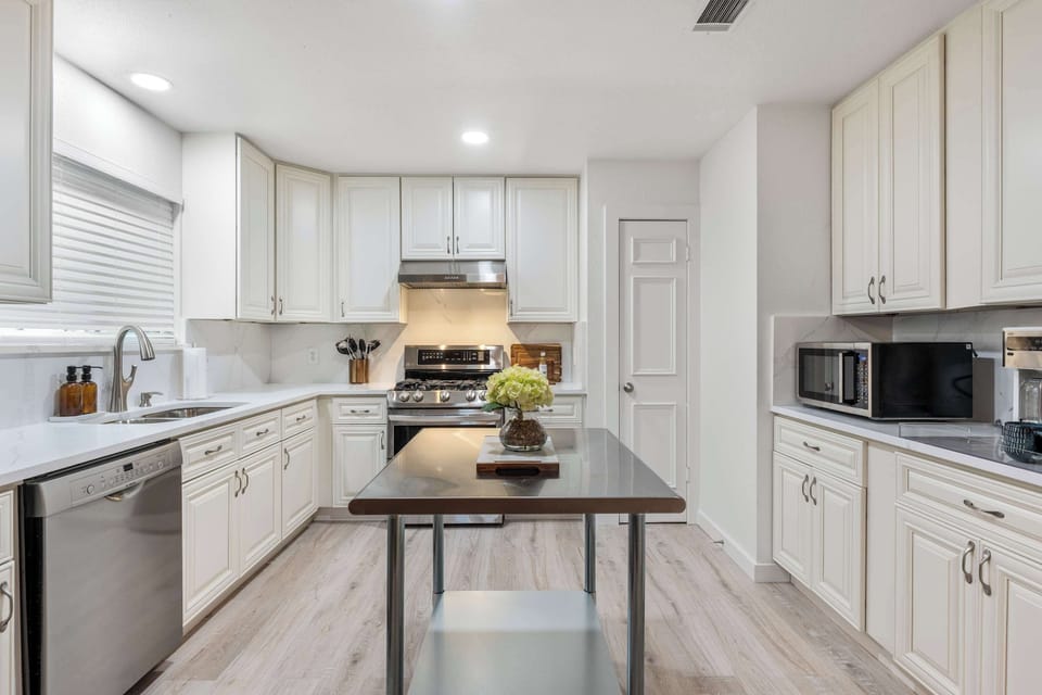 The bright, modern kitchen features quartz countertops, stainless steel appliances, a chef's stainless steel island, and a welcoming eat-in dining space for shared meals.