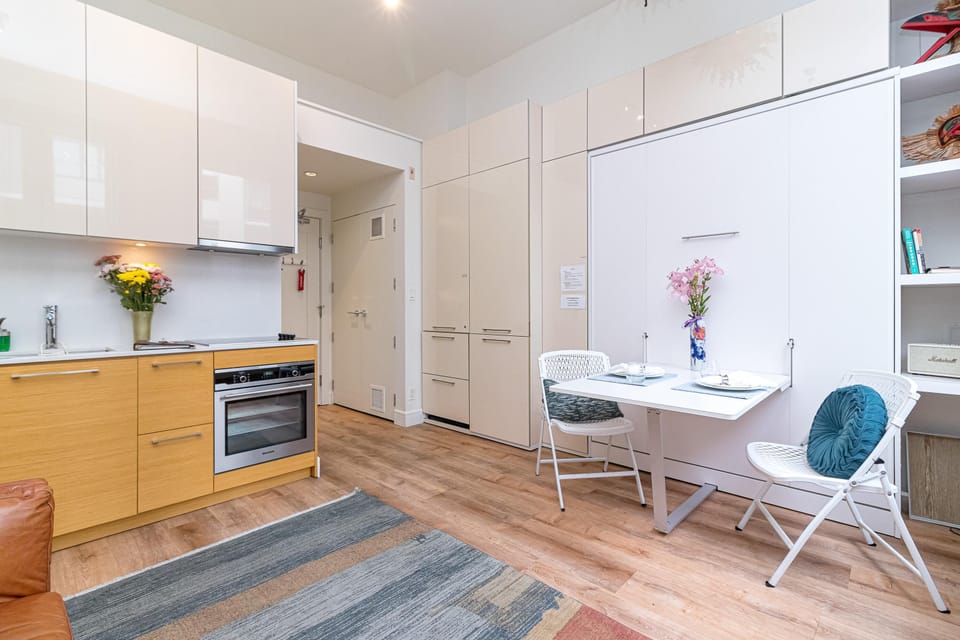 White fold-down table with two white chairs and built-in storage cabinets in the kitchen area.