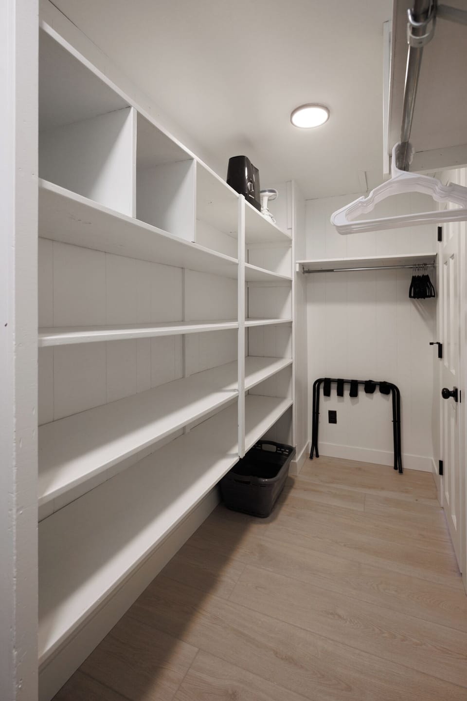 Spacious walk-in closet with shelves, hangers, and a luggage rack.