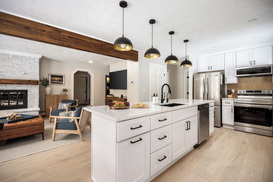 Bright quartz-island kitchen, stainless apps, open to a cozy fireplace lounge.