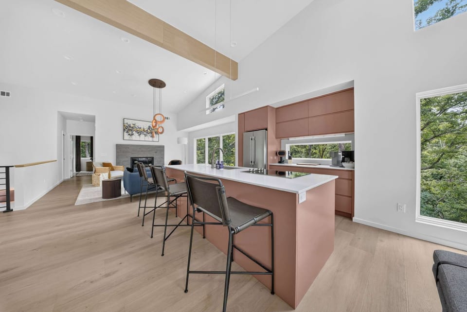 The chef's kitchen features a large island, bar seating, and warm designer cabinetry.