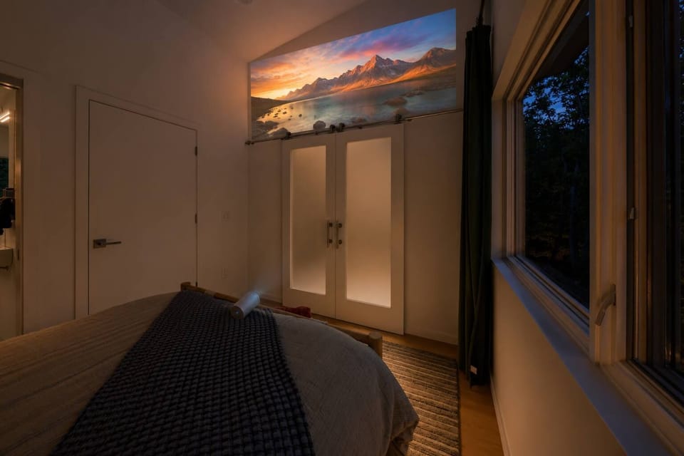 A calm, cocooning bedroom with a flexible projector that connects to your phone for streaming your favorite shows and winding down.