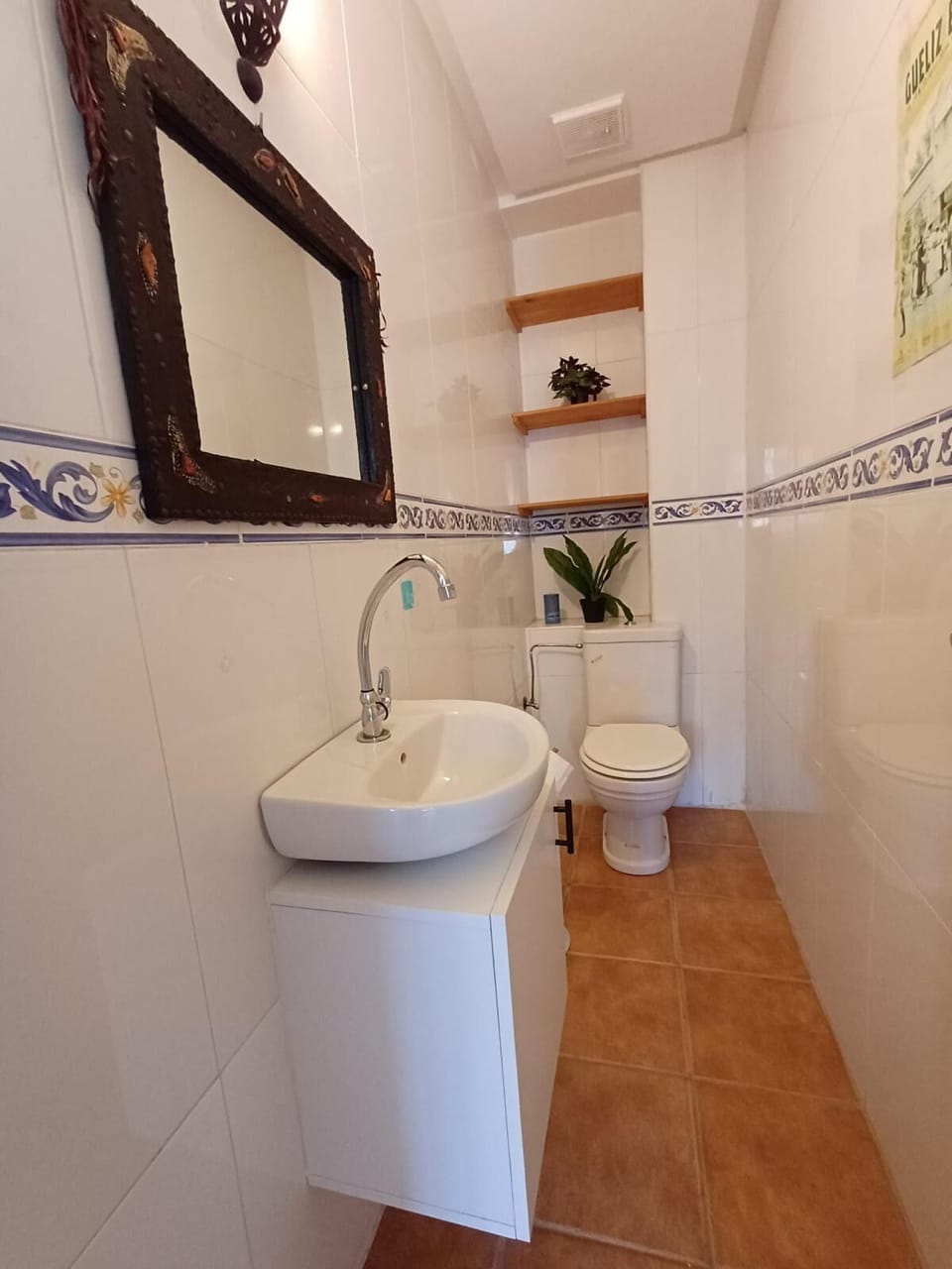 Clean guest bathroom with modern sink vanity, toilet, and traditional tiles.