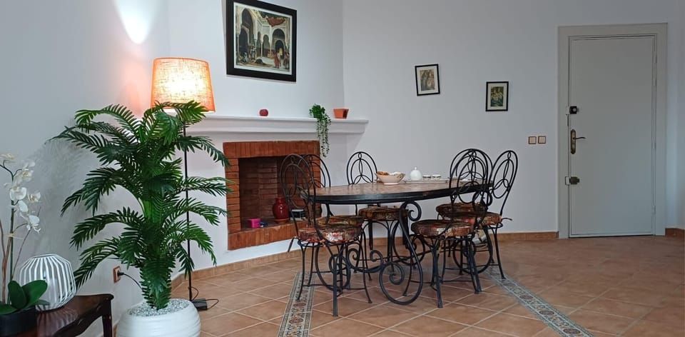 Wrought-iron dining table set next to a charming brick fireplace.