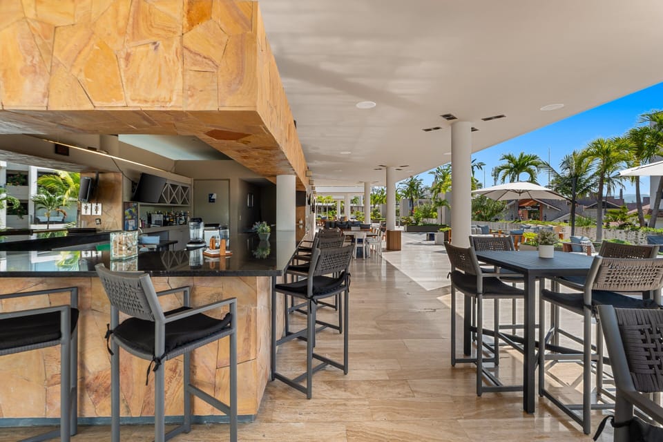 Relax at the spacious stone-accented bar or high-top tables in this covered terrace, offering the perfect spot to mingle and enjoy the warm breeze.