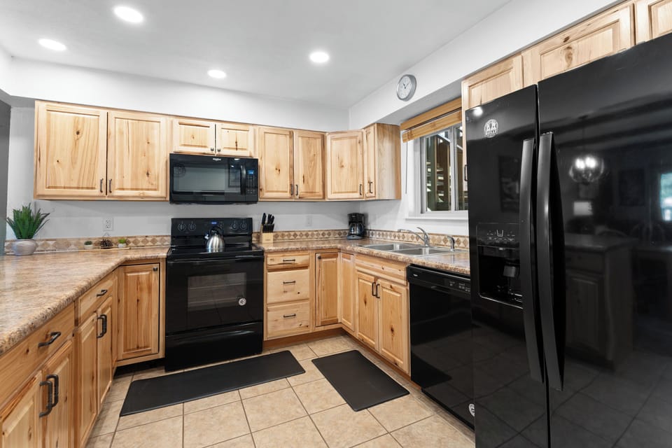A well-equipped kitchen with natural wood cabinetry and modern black appliances awaits your culinary adventures, complete with granite countertops and everything you need to prepare your favorite meals.