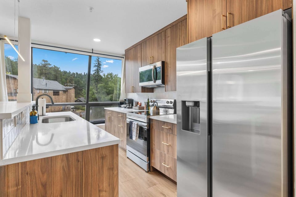 The kitchen has stainless steel appliances and a beautiful view of Evergreen.