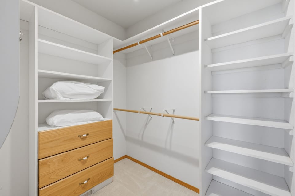 Your spacious walk-in closet features custom shelving, natural wood accents, and dedicated hanging space to keep your wardrobe perfectly organized during your stay.
