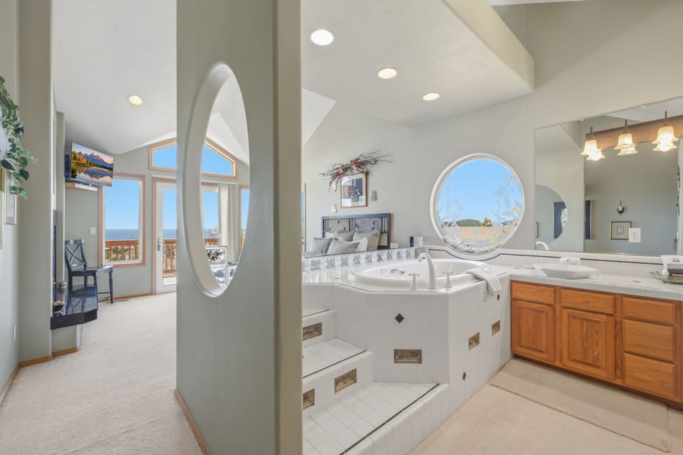 Sink into your luxurious jetted tub while gazing through the unique circular window at scenic views. This spa-like bathroom invites you to unwind in comfort and style.