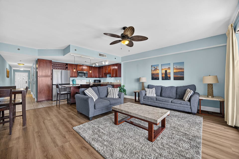 Sink into plush seating in your open-concept living space, where coastal-inspired décor and a breezy ceiling fan create the perfect ambiance for unwinding after sun-soaked beach days.