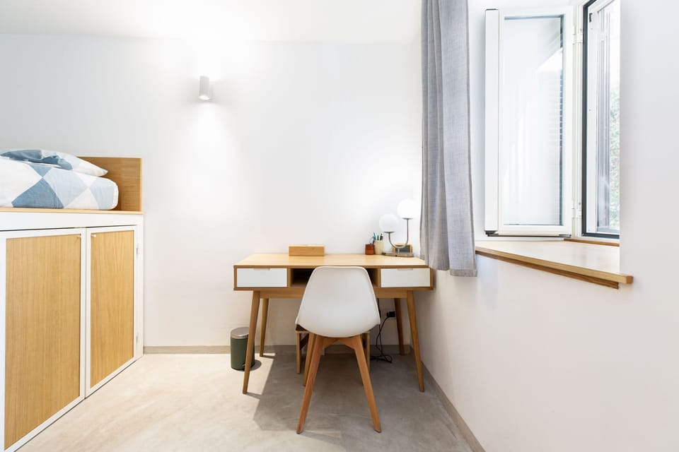 A proper desk by the window, full size, not a side table