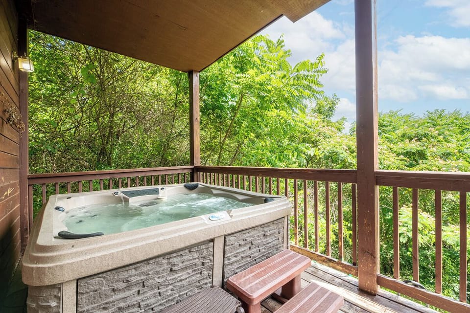 Soak in your private hot tub on the covered deck, surrounded by lush trees and fresh mountain air—perfect for unwinding after a day exploring nearby trails.