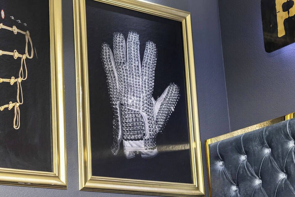 Step into a unique ambiance highlighted by striking art, including a framed glove that sparks curiosity. The rich texture of the tufted wall complements the dark tones, creating a stylish backdrop for relaxation or conversation.