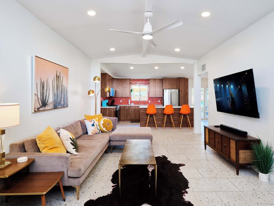 Bright, open living room blending mid-century charm with modern comfort, featuring a Smart TV, iconic fireplace, and spacious seating for gathering and unwinding.
