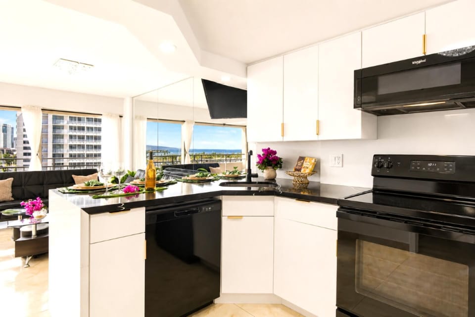 A sleek, fully stocked kitchen with black-granite counters, full-size range and dishwasher, and an ocean view through the window while you cook. ILK-937