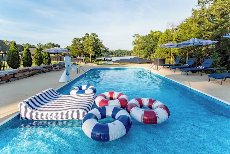 Resort-style waterfront pool with loungers, umbrellas, and fun floats