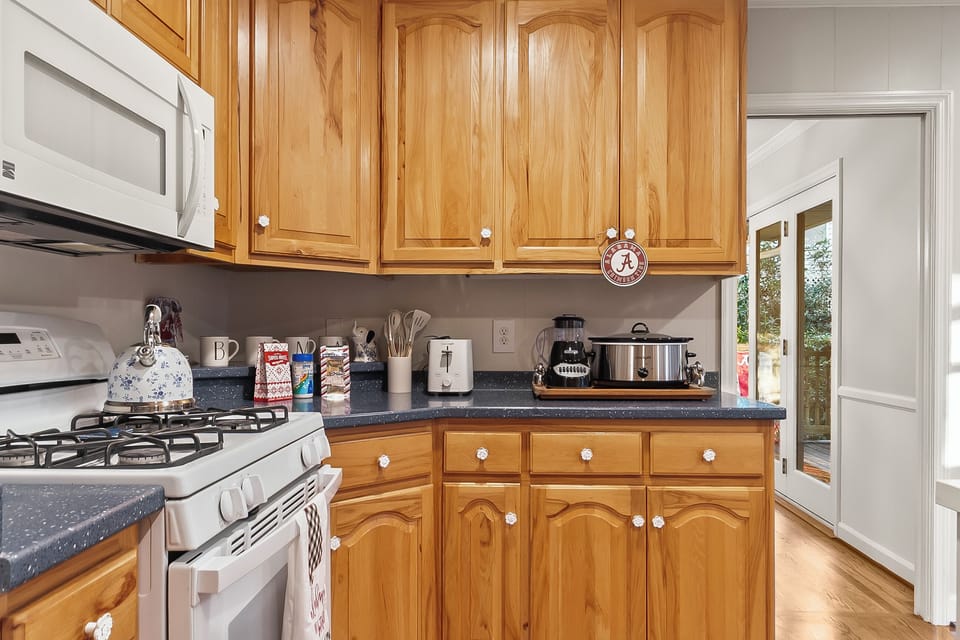 Bright, fully equipped kitchen with warm wood cabinets and outdoor access