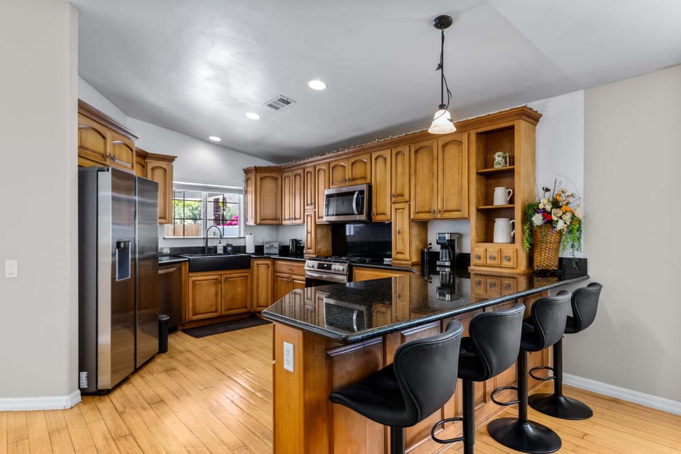 Stainless steel appliances, coffee maker, granite counters, and counter seating for 4 guests.
