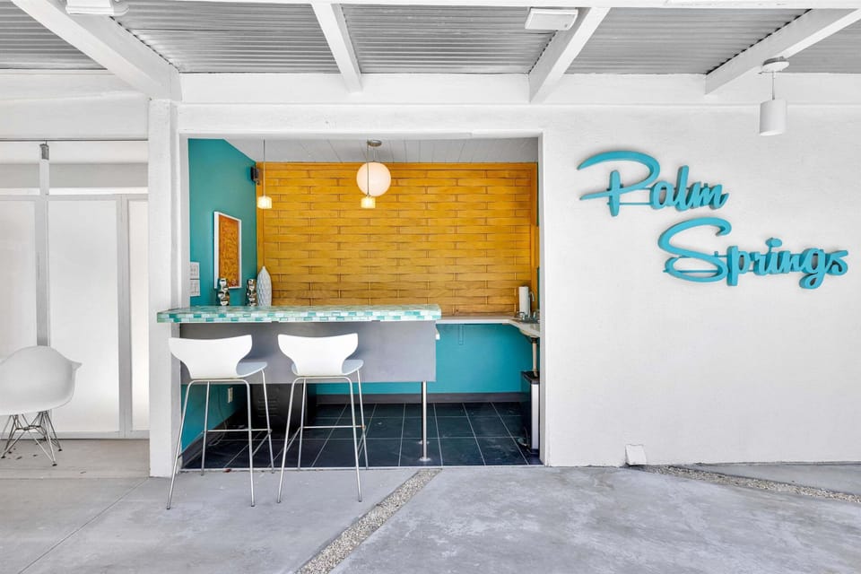 Covered poolside bar with seating and colorful Palm Springs style