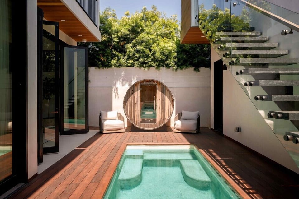 Wood decking, a cozy plunge pool, and a rustic barrel sauna make this backyard feel like a private spa.