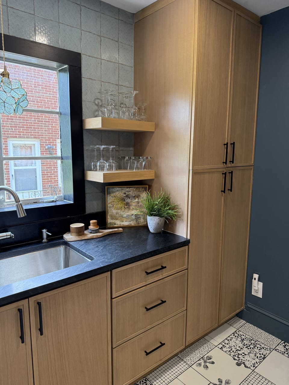 Stylish wet bar with custom cabinetry, open shelving, and chic tile floors