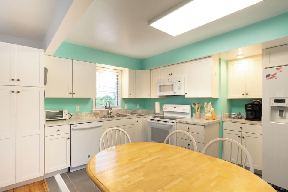 Step into your bright, fully-equipped kitchen where cheerful turquoise walls and granite counters set the stage for home-cooked meals. Natural light streams in, inviting you to start each morning here.