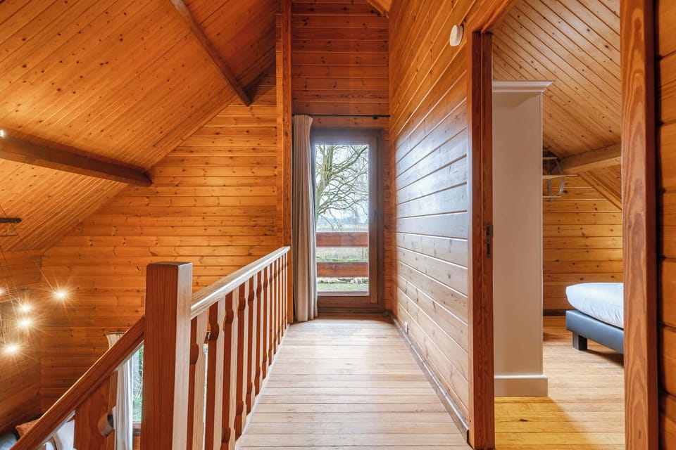 The mezzanine landing leads to the sleeping quarters. Private, warm, and full of chalet character.