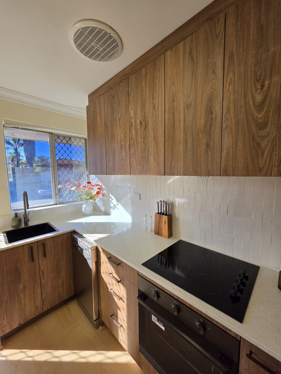 Bright modern kitchen with sunlit window, sleek finishes, and warm wood tones