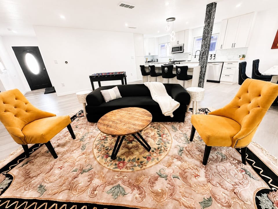 Bright open living area with stylish seating, game table, and modern kitchen