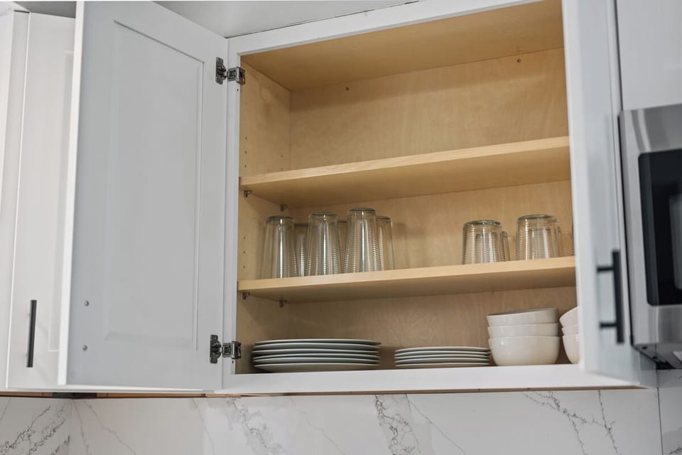 Well-stocked modern kitchen cabinet with plates, bowls, and glassware