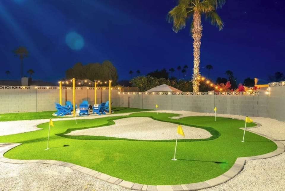 A backyard putting green under string lights and palm trees, because vacation should include a few rounds of mini golf before bed. Multiple holes mean the whole group can play at once.
