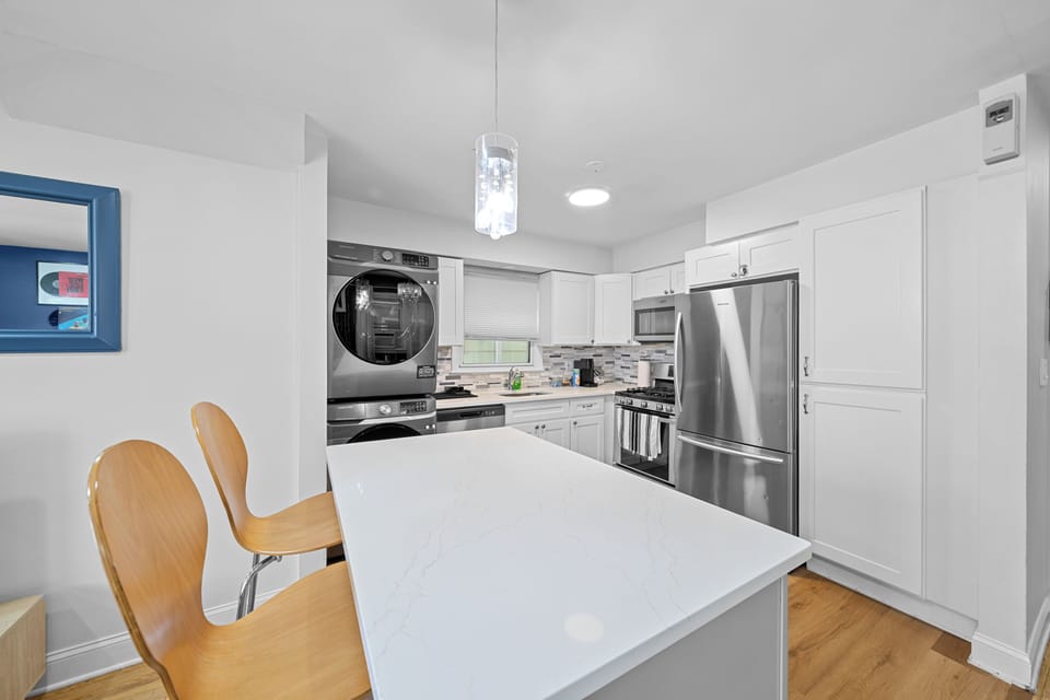 Bright modern kitchen with island seating, stainless appliances & in-unit laundry