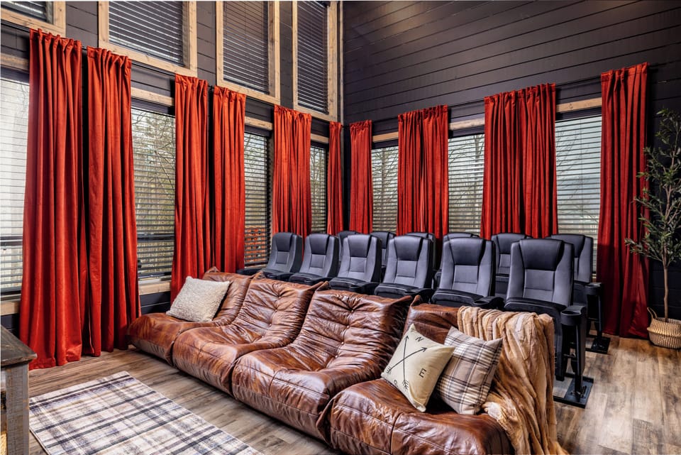 Private theater room with leather sectional, reclining seats, and soaring windows