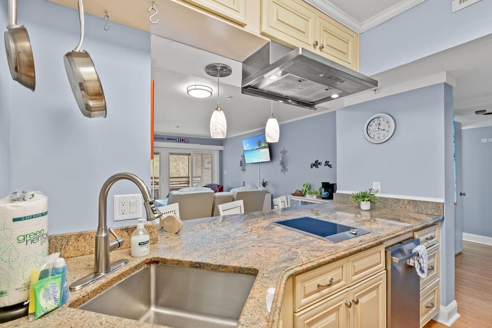 Granite kitchen with island seating, induction cooktop, and open living view
