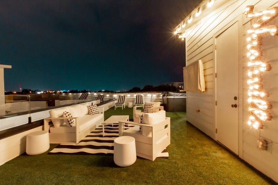 Relax under the stars on the spacious rooftop terrace featuring luxury patio furniture and warm string lights.