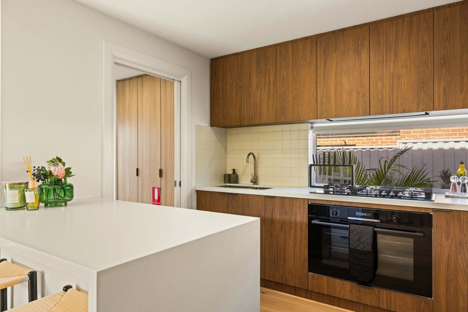 Enjoy meal preparation in this modern, stylish kitchen equipped with rich wood-finish cabinetry, sleek white countertops, a gas cooktop, and an integrated oven. 