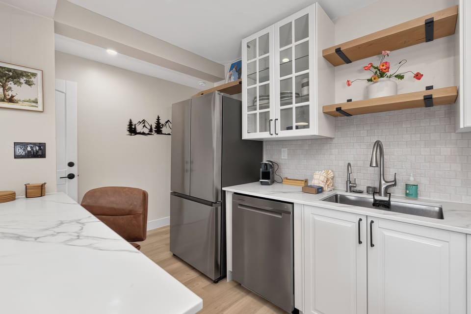 Your modern kitchen awaits with sleek stainless appliances, crisp white cabinetry, and open shelving where you can display your finds from local markets. The spacious countertops give you plenty of room to prepare meals together.