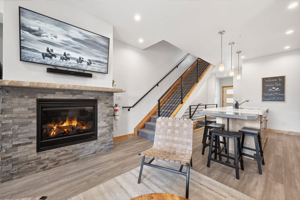 Unwind by the warm fireplace, perfect for your après-ski evenings. Modern living meets mountain charm with high ceilings, stylish seating, and a welcoming open layout.