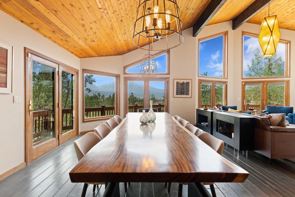 Gather around this stunning live-edge dining table under vaulted wood ceilings, where panoramic mountain views frame every meal. The open layout flows into the living area, creating your perfect retreat.