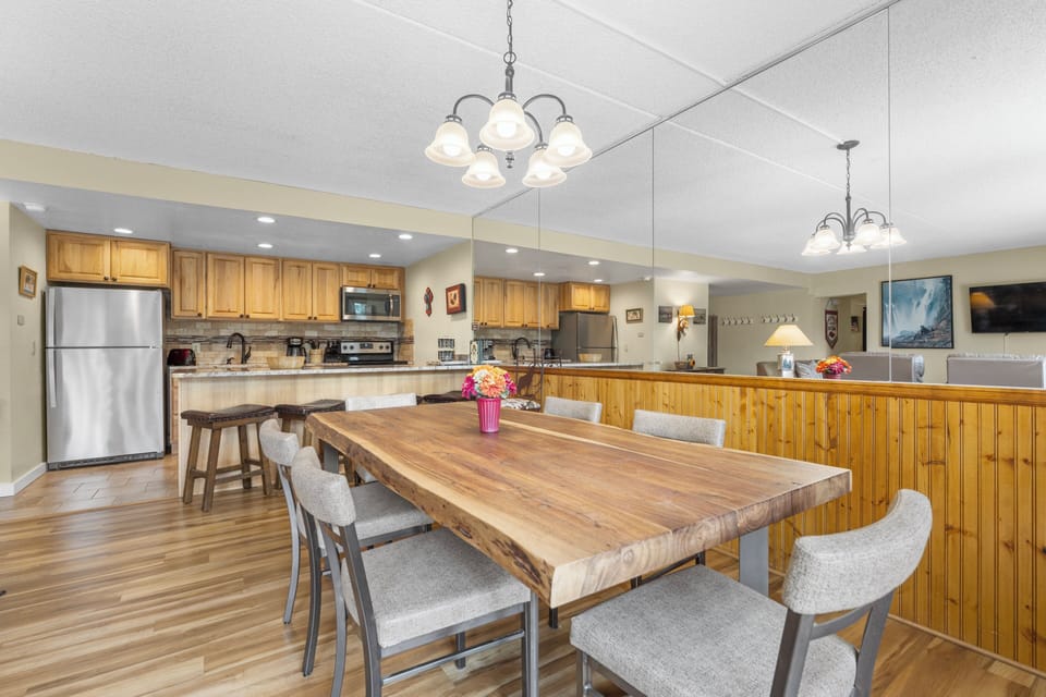 Gather around this spacious table in your fully equipped kitchen, where warm wood tones and modern appliances create the perfect setting for shared meals and lasting memories.