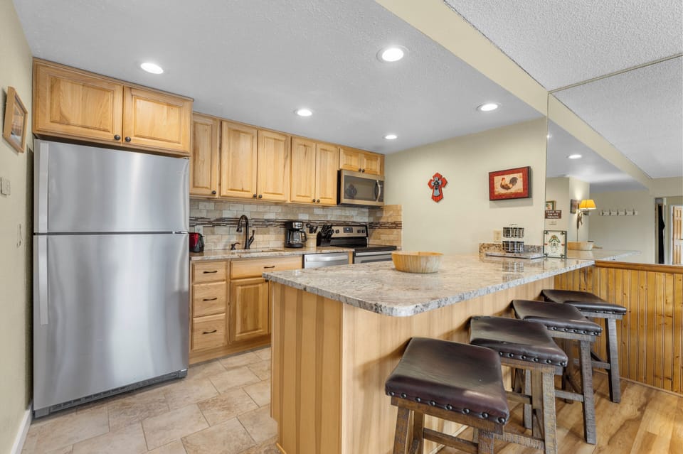 Your fully equipped kitchen features granite countertops, stainless steel appliances, and a breakfast bar—perfect for preparing meals and gathering with loved ones during your stay.