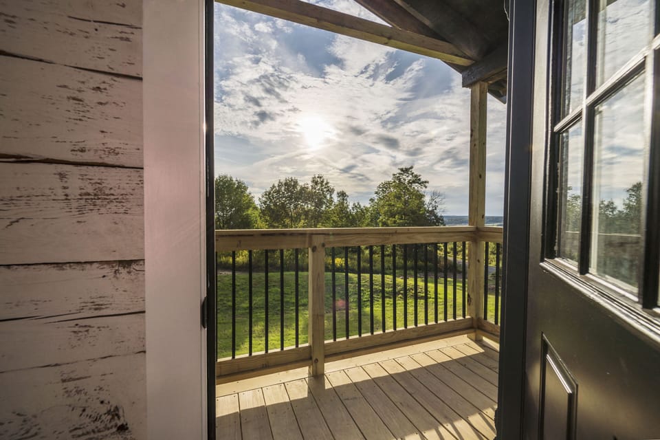 Private covered balcony with scenic green views and a water glimpse