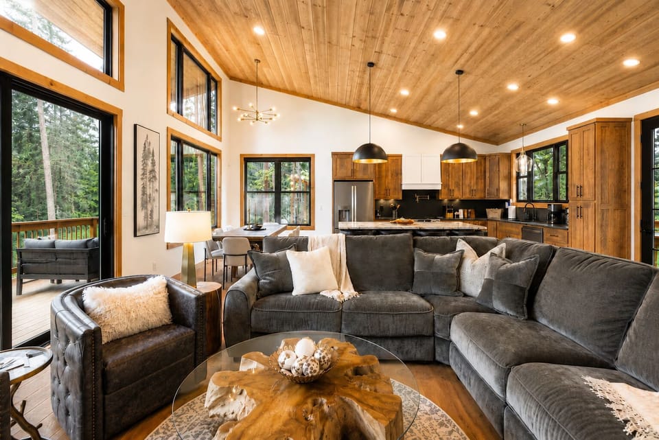 Cozy great room with forest views, vaulted wood ceilings, and modern kitchen