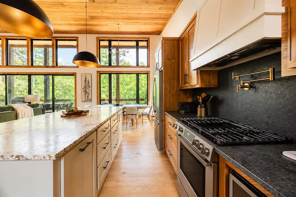 Bright designer kitchen with oversized island and stunning forest views
