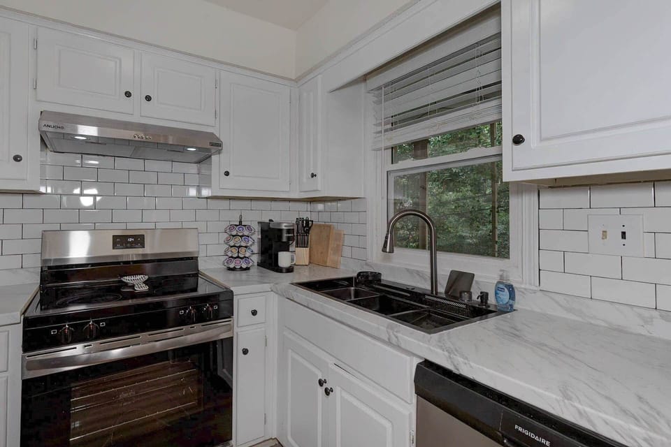 Renovated kitchen with subway tile, marble-look counters, and a sunny window over the sink