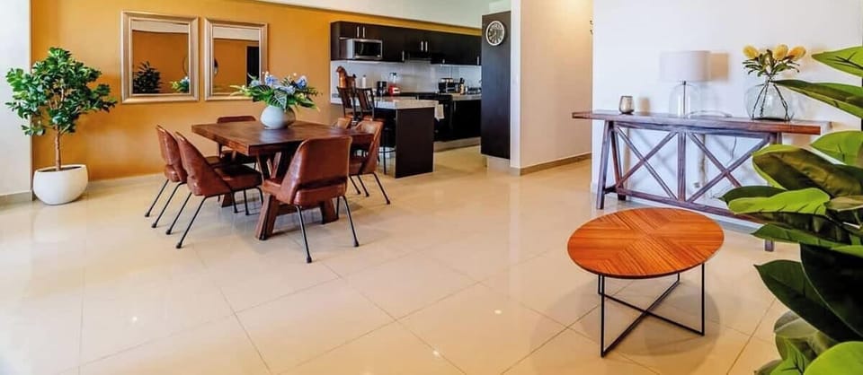 Comedor junto a espacio de recibidor y cocina al fondo.
