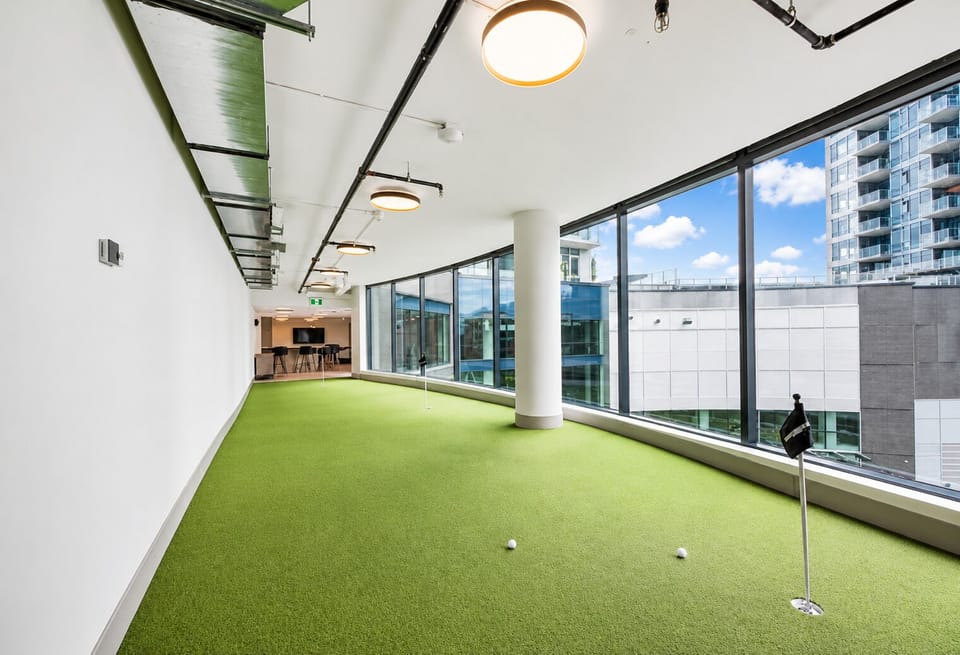 Bright indoor putting green with floor-to-ceiling city views