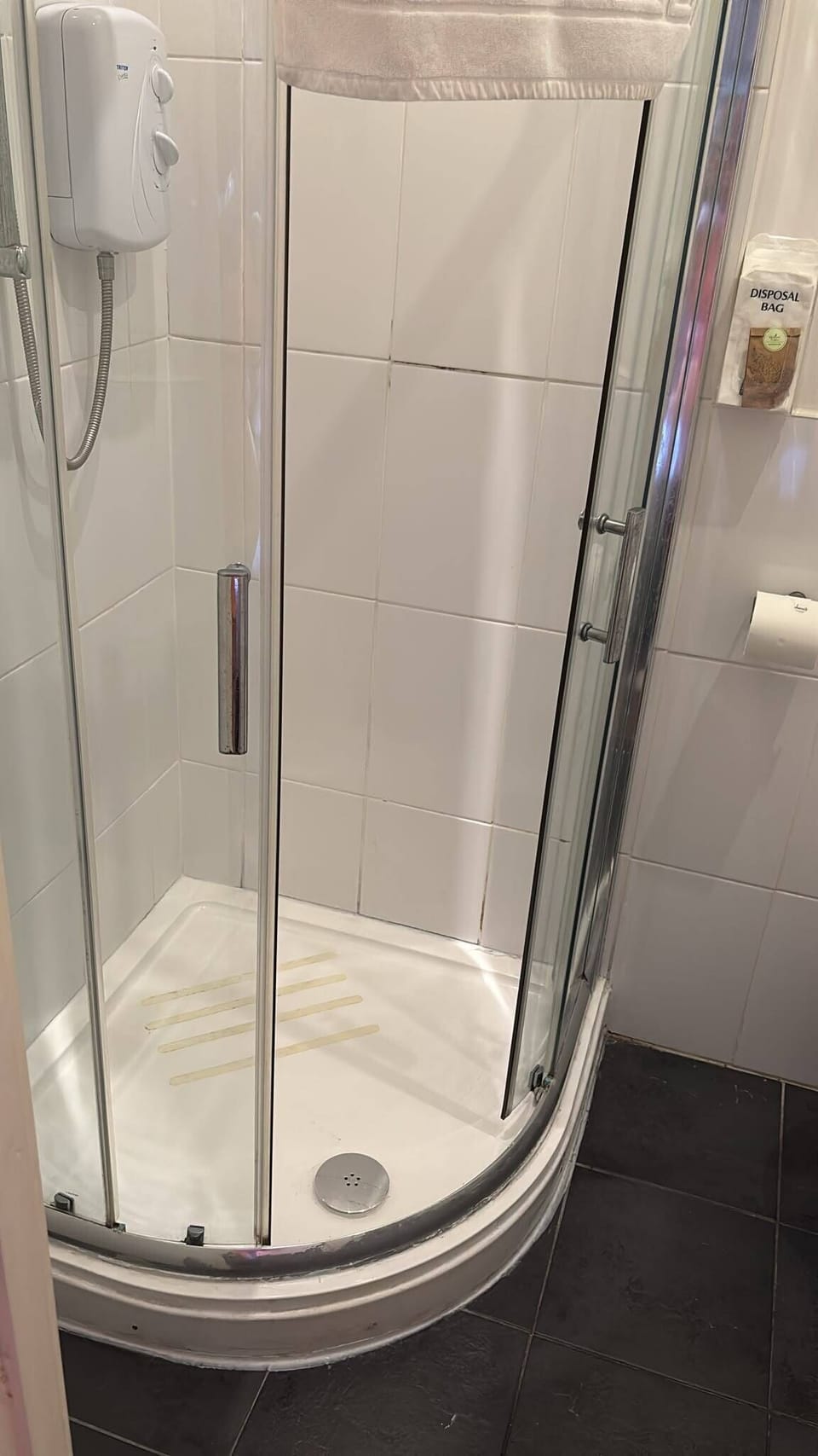 Bright tiled bathroom with enclosed glass shower and modern electric unit